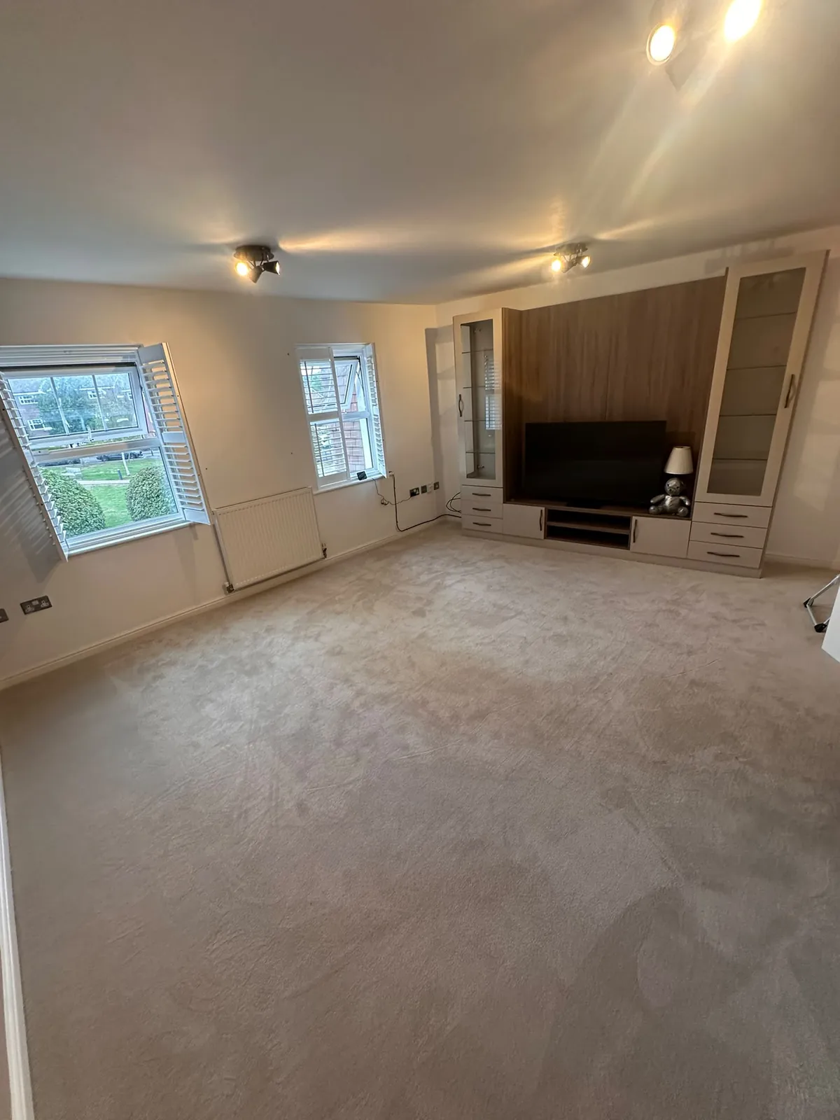 Second view of the lounge with fitted TV unit showing existing worn carpet before uplift — Bromley BR1