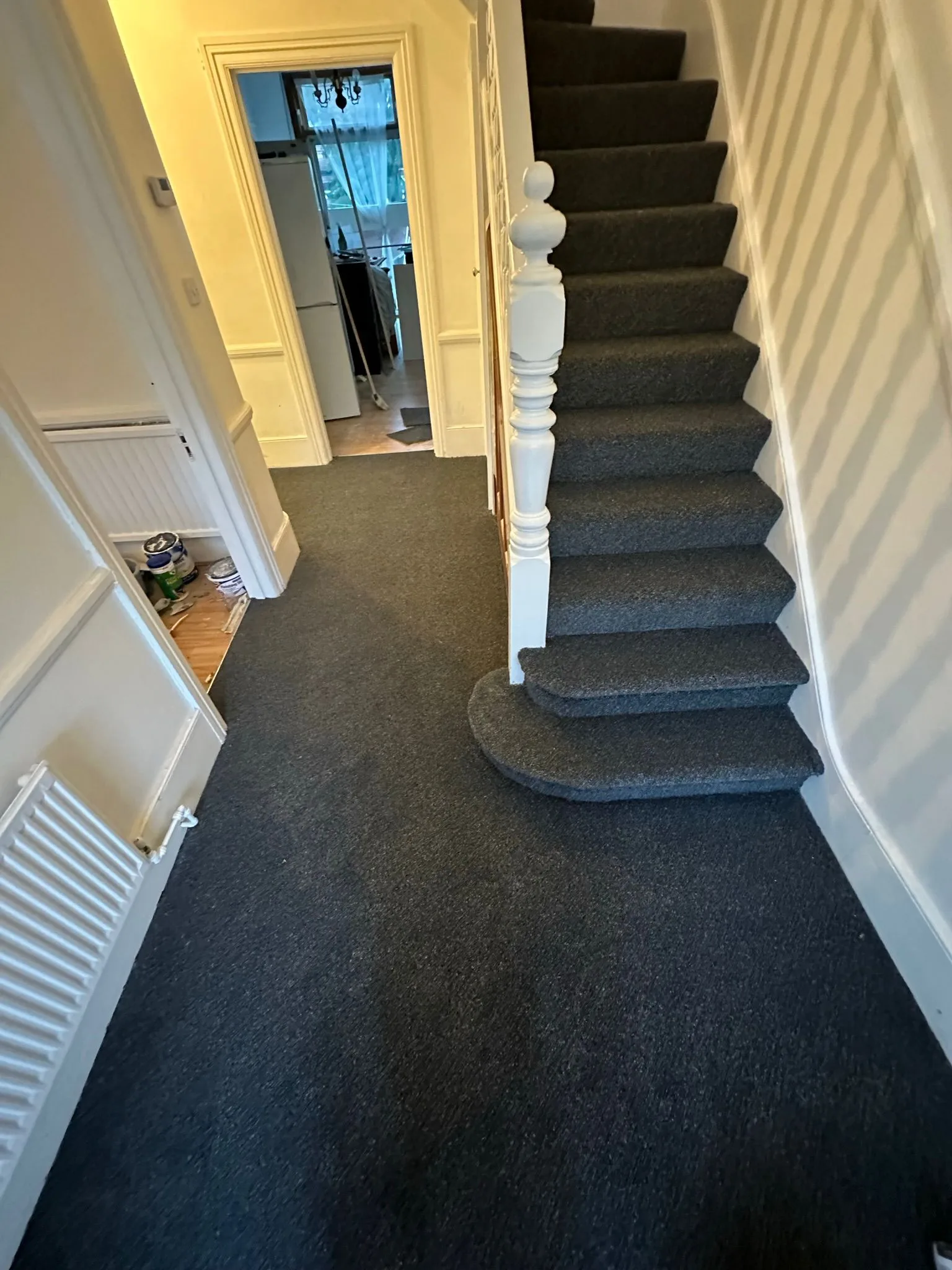 Dark charcoal carpet professionally fitted in a residential hallway and staircase with white balustrade